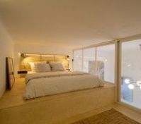 Cozy loft-style sleeping area with a minimalist touch, perfect for restful nights. Nestled on the upper level of our compact apartment, this elevated bed setup features soft bedding, warm lighting, and a calming wooden aesthetic. 