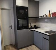 This is the kitchen.  The refrigerator is under the oven on the left.  The washing machine is under the counter.  The door on the left leads to the WC