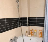 Bathtub with shower and tiled walls