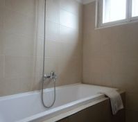 Bathtub with shower and tiled walls