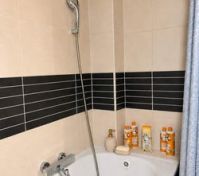Bathtub with shower and tiled walls